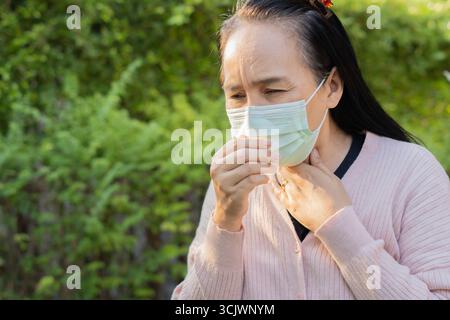 Femme se sentant malade, toussez et éternuez avec le port d'un masque de protection du visage à l'extérieur. Copier l'espace. Concept sain. Banque D'Images