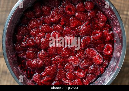 Framboise rouge fraîche, recouverte de sucre granulé pour la préparation de confiture dans un bol, vue de dessus, gros plan. Fond et texture des framboises avec s Banque D'Images