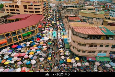 Accra, Ghana - 23 mars 2024 : la vue aérienne du marché de Makola éclate avec une tapisserie vibrante de parapluies colorés ombrageant les foules animées au milieu des textures architecturales de la ville. Banque D'Images