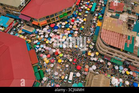 Accra, Ghana - 23 mars 2024 : vue aérienne du chaos animé du marché de Makola, une mer de parasols colorés et une foule animée nichée entre les bâtiments. Banque D'Images
