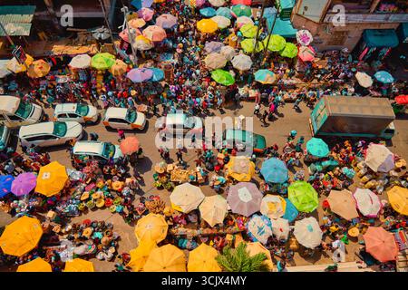 Accra, Ghana - 05 novembre 2022 : vue aérienne du marché de Makola regorgeant de parapluies vibrants, de foules animées et de marchandises colorées créant une tapisserie animée de commerce et de culture. Banque D'Images