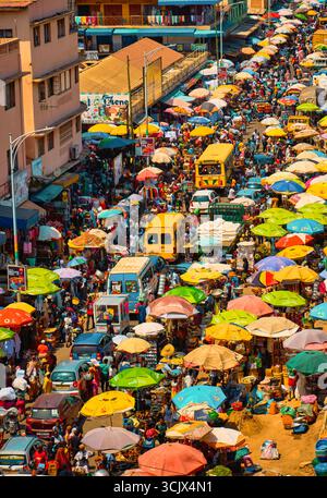 Accra, Ghana - 05 novembre 2022 : vue aérienne du chaos vibrant du marché de Makola, une tapisserie dense de parapluies colorés ombrageant les foules animées et des bus jaunes circulant dans les rues animées. Banque D'Images