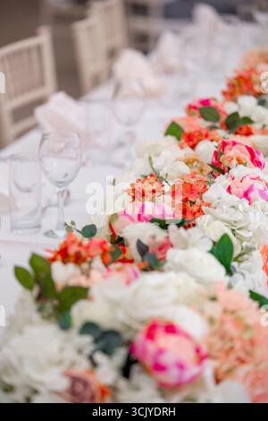 Pièce maîtresse de table lors d'une réception de mariage avec un arrangement floral luxuriant en cascade avec des fleurs blanches, blush et roses Banque D'Images