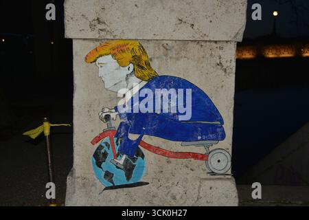 Graffiti politique à Rome, Italie (2019) représentant une caricature de Donald Trump chevauchant un tricycle avec la Terre comme roue avant, rue satirique Banque D'Images