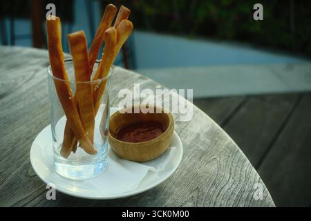 Un apéritif de pailles de fromage, une collation salée servie avec une sauce tomate Banque D'Images