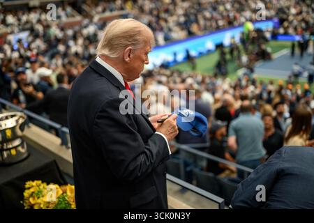 Le président Donald J. Trump signe une casquette pour un supporter alors qu’il assiste au championnat masculin de l’US Open lors de la finale masculine de l’US Open au stade Arthur Ashe dans le Queens, NY. USTA Billie Jean King National Tennis Center le 7 septembre 2025. Banque D'Images