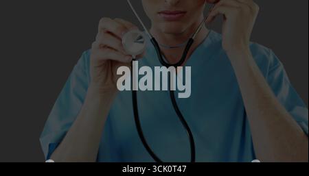 Médecin présentateur portant des gommages bleus maintenant le diaphragme du stéthoscope contre la paroi grise, avec tubulure Banque D'Images