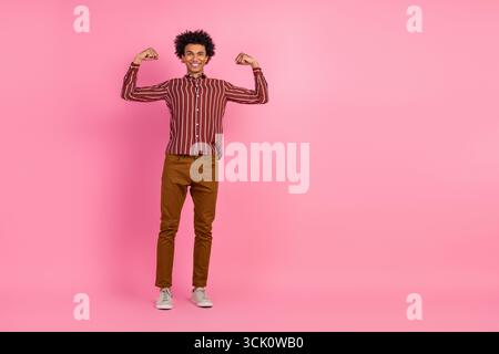Jeune homme confiant dans une tenue décontractée élégante pose sur fond rose vif montrant la force et la positivité Banque D'Images