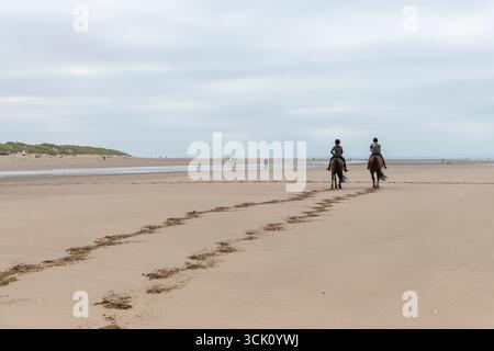 Deux jeunes cavalières sur la plage de Formby point sur la côte de Sefton, Merseyside, Angleterre. Banque D'Images