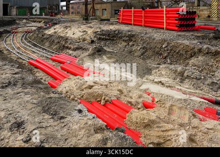 Pose d'un nouveau câble d'alimentation haute tension souterrain en tube de protection ondulé rouge pour l'alimentation d'une installation industrielle, installation de câble Banque D'Images
