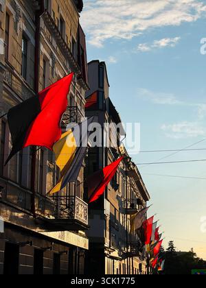 Drapeaux ukrainiens colorés sur les bâtiments urbains avec la lumière du coucher du soleil et une atmosphère vibrante. Banque D'Images