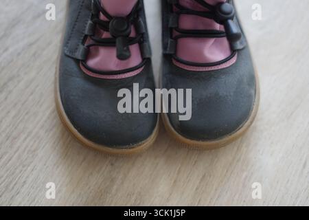 Une paire élégante de chaussures noires et roses repose sur un plancher en bois pieds nus hiver froid chaud Banque D'Images