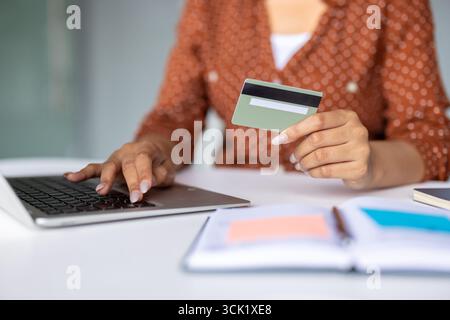 Femme d'affaires tenant la carte de crédit et tapant sur le clavier d'ordinateur portable, rendant le paiement en ligne sécurisé pour des biens ou des services, gérant les finances efficacement Banque D'Images