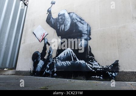 Londres, Royaume-Uni. 9 septembre 2025. Une nouvelle œuvre du célèbre artiste de rue anonyme BANKSY est apparue devant les cours royales de justice hier, représentant un juge de la cour portant son marteau sur un manifestant prostré tenant une pancarte. Elle fait suite à l'arrestation deux jours plus tôt de 857 manifestants pacifiques sur la place du Parlement tenant des pancartes soutenant l'action palestinienne. Cachée par un écran protecteur en métal, l'œuvre d'art était visible aujourd'hui à travers un petit espace et les gens faisaient la queue pour avoir un aperçu. On ne sait pas encore ce qui arrivera au graffiti. Crédit : Ron Fassbender/Alamy Live News Banque D'Images