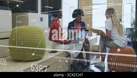 Collaboration de trois collègues femmes utilisant un ordinateur portable, une tablette et tenant un dossier jaune dans le salon du bureau Banque D'Images