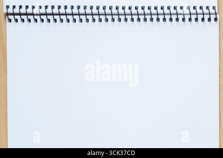 toile de fond abstraite : gros plan de la page blanche du carnet de croquis avec reliure à spirale posée sur la table Banque D'Images