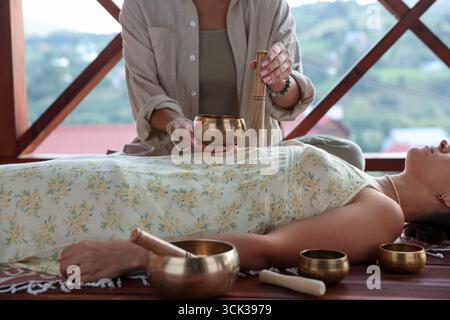 Femme subissant une thérapie de bol chantant couchée sur le sol à l'intérieur, gros plan Banque D'Images