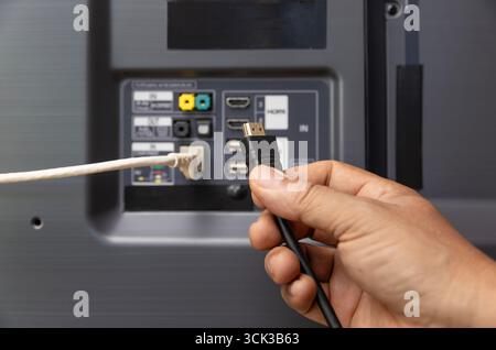 Man connecte le câble Internet au téléviseur. Banque D'Images