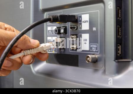Man connecte le câble Internet au téléviseur. Banque D'Images