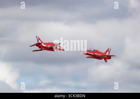 Deux BAE Hawk Advanced Jet Trainers des Red Arrows de la RAF effectuent une passe d'opposition rapprochée risquée lors du Royal International Air Tattoo. Banque D'Images