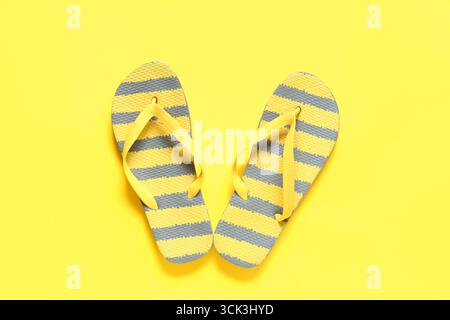 Tongs rayées élégantes sur fond jaune Banque D'Images