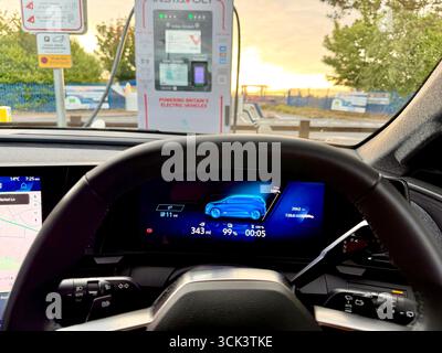 Un tableau de bord de voiture électrique affichant 99% chargé connecté à un point de charge rapide EV au Royaume-Uni Banque D'Images