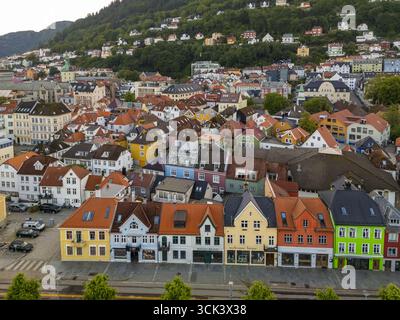 Vue aérienne de bâtiments vibrants avec des toits de tuiles rouges contrastant avec la colline verdoyante dans une scène pittoresque., Bergen, Vestland, Norvège. Banque D'Images