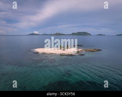 Vue aérienne d'une petite île sablonneuse entourée d'eaux turquoises, avec des îles lointaines à l'horizon, Fidji. Banque D'Images