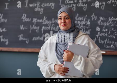 Portrait de jeune femme adulte du moyen-Orient tenant cahier dans l'école de langue Banque D'Images