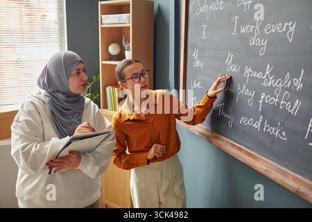 Jeune femme caucasienne enseignant la grammaire anglaise à la jeune femme du moyen-Orient Banque D'Images