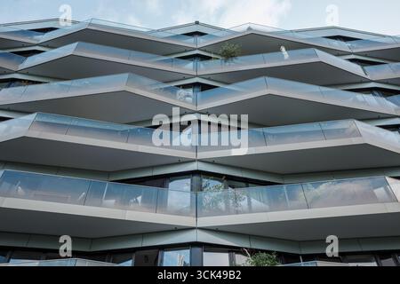 Une photographie symétrique, en angle bas, de la façade d'un immeuble futuriste. L'architecture présente un motif de chevrons frappant en forme de V. Banque D'Images