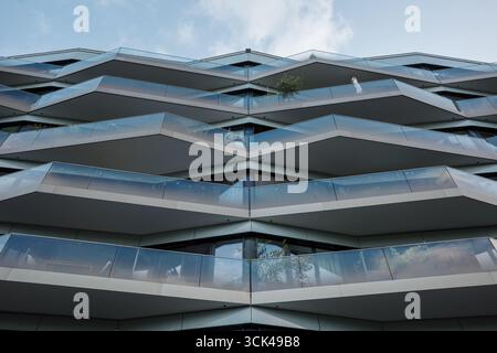 Une photographie symétrique, en angle bas, de la façade d'un immeuble futuriste. L'architecture présente un motif de chevrons frappant en forme de V. Banque D'Images