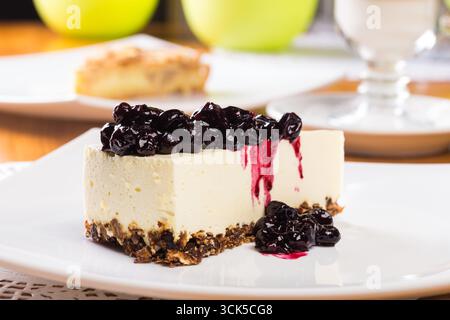 Tranche de cheesecake avec le dessus de confiture de myrtilles sur une assiette blanche Banque D'Images