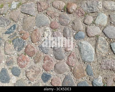 Ancien pavé pavé avec des pierres naturelles et de l'herbe Banque D'Images