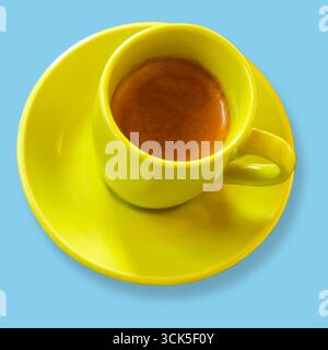 Une tasse à café jaune vif remplie d'espresso, assise sur une soucoupe assortie, présentant une boisson chaude et accueillante. Banque D'Images