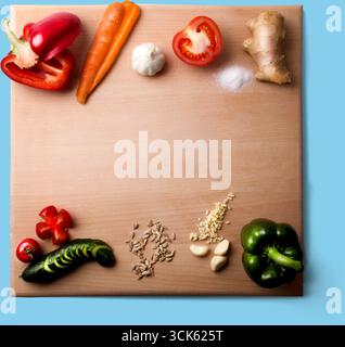 Une planche à découper en bois avec divers légumes frais et ingrédients disposés pour la préparation de la cuisson. Banque D'Images