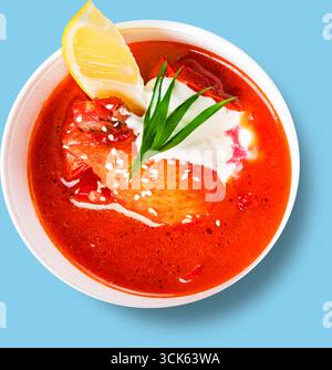 Un bol vibrant de soupe avec du poulet, garni d'herbes et d'un coin de citron, parfait pour un repas copieux. Banque D'Images