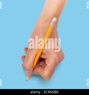 Une main tenant un crayon jaune, prête à écrire ou à dessiner. Banque D'Images