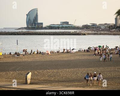 Barcelone, Espagne. 06 septembre 2025, touristes appréciant la plage de Barceloneta avec W Barcelona Hotel en arrière-plan Banque D'Images