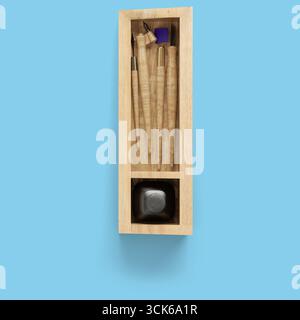 Boîte en bois contenant divers outils d'écriture et une bouteille d'encre, conçue pour la calligraphie ou l'écriture artistique. Banque D'Images