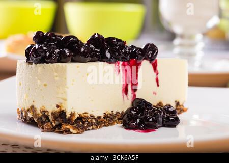 Tranche de cheesecake avec le dessus de confiture de myrtilles sur une assiette blanche Banque D'Images