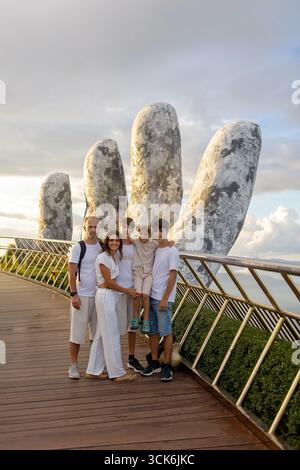 Famille avec enfants, visitant le Pont d'Or avec de grandes mains dorées le tenant à Da Nang, Ba Ha Hills destination de voyage, Vietnam Summertime sur su Banque D'Images