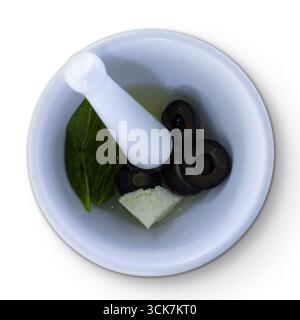 Mortier et pilon contenant des olives, du fromage et du basilic dans l'huile, idéal pour la préparation des aliments. Banque D'Images