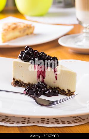 Tranche de cheesecake avec le dessus de confiture de myrtilles sur une assiette blanche Banque D'Images