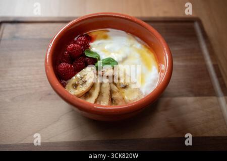Yaourt avec bananes et framboises fait un délicieux petit déjeuner Banque D'Images