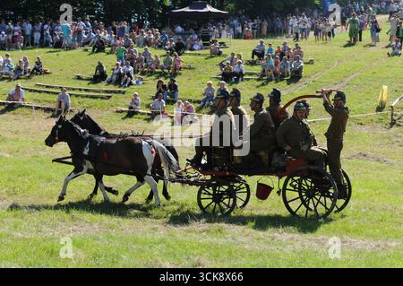 Pompiers en uniformes vintage chevauchant une pompe à incendie tirée par un cheval pendant la compétition avec des spectateurs en arrière-plan, Rudawka Rymanowska, Podkarpackie, po Banque D'Images