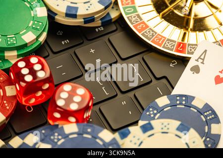 Image composite haute résolution de jetons de casino, ordinateur portable fermé, roues de roulette en mouvement, cartes à jouer as de pique, as de cœur, et conçu pour M. Banque D'Images