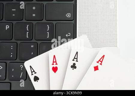 Une image fractionnée avec un ordinateur portable montrant le code et les cartes à jouer en forme d'éventail sur le côté droit le contexte suggère des thèmes de la technologie, du jeu, Banque D'Images