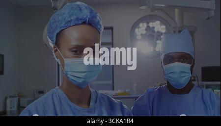 Chirurgiens debout portant des gommages bleus et des masques dans la salle d'opération, lampe chirurgicale, plateau d'instruments Banque D'Images