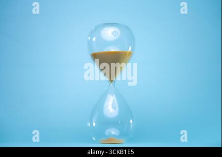 Raconter l'heure avec un sablier avec du sable coulant à une certaine distance. Sablier transparent. Banque D'Images